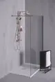 Duschsystem mit Aluminiumstruktur, zwei Ablagen und Brausearm, an einer Wand montiert. Ideal Standard Design mit Klarglas-Trennwand und Handtuchhalter neben der Dusche.